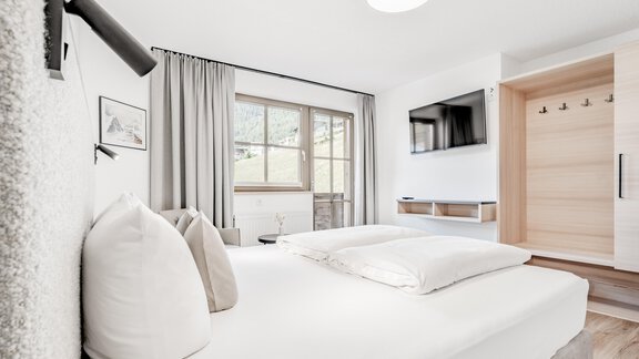 A bright bedroom with a large double bed and modern furniture. A window overlooking nature provides natural light. - Appartement Montanara - Sölden