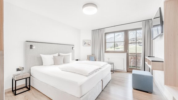 A modern bedroom with a large double bed and plenty of natural light. The elegant decor creates a cozy atmosphere. - Appartement Montanara - Sölden