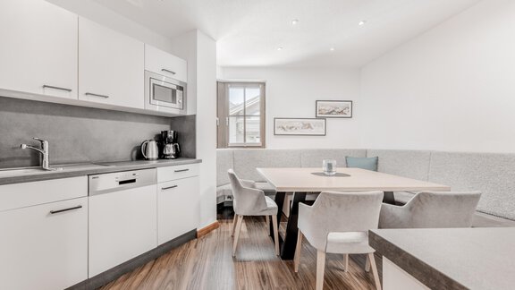 A modern kitchen with a dining table and elegant chairs. The room design is bright and inviting. - Appartement Montanara - Sölden