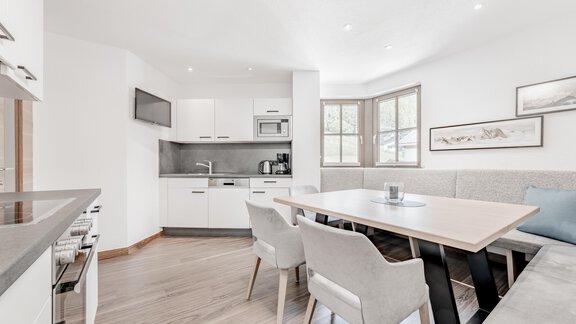 A modern kitchen with a dining area and elegant chairs. Large windows provide plenty of natural light. - Appartement Montanara - Sölden
