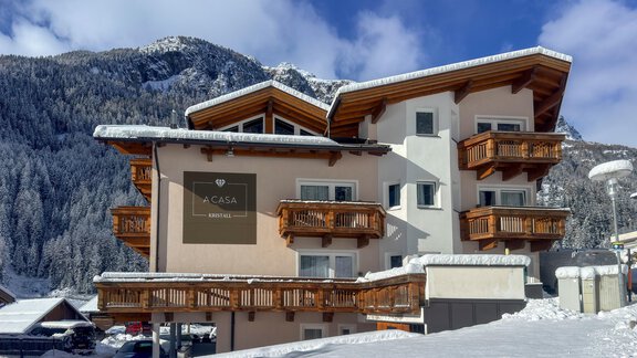 A modern building in the snow, surrounded by mountains. The facade has wooden balconies and a sign that reads "La Casa". - Appartementhaus A CASA "Kristall" - Sölden