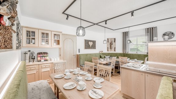 A bright and modern dining room with wooden chairs and a large table. There is a cozy seating area and an open kitchenette. - Appartementhaus Kathrin - Sölden