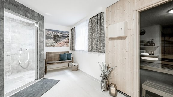 A modern bathroom with a shower and a sauna. The room is bright and inviting, with wood and color accents. - Appartementhaus Kathrin - Sölden
