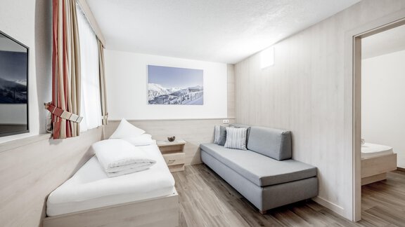 A modern room with a cozy sofa bed and two beds. The walls are bright and the window lets in plenty of daylight. - Appartementhaus Kathrin - Sölden