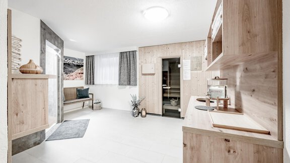 A bright room with modern wood decor and a window that lets in natural light. On the left side, there is a cozy seating area and a decorative plant. - Appartementhaus Kathrin - Sölden