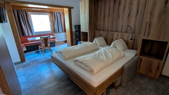 A modern living room with a fully integrated living area. In the background, there is a table with chairs and a window visible. - Appt. Rosmarie - Sölden