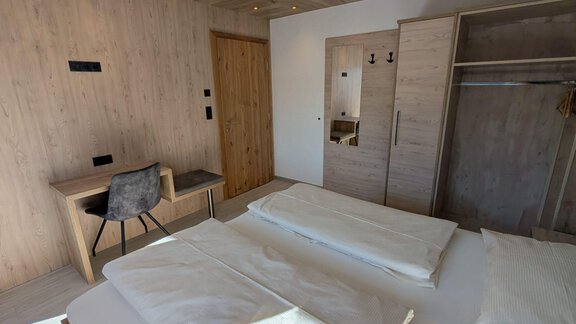 A modern hotel room with two beds, a desk, and a wooden wardrobe. The walls are bright and the decor is simple and elegant. - Appt. Rosmarie - Sölden