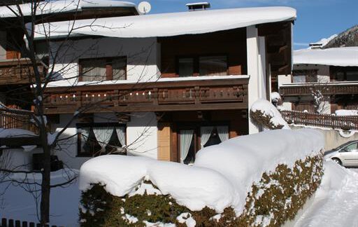A snow-covered house with a balcony surrounded by snow. The sky is clear and blue. - Appt. Schnöller - Sölden