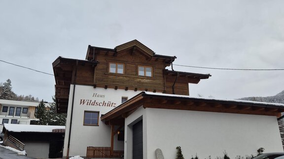 A traditional house with wooden cladding and a modern extension. Snow-covered streets and a peaceful atmosphere surround the building. - Appt. Wildschütz - Sölden