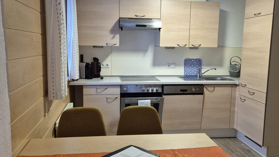 A modern kitchen with light wood cabinets and a dining table. The room design is bright and inviting. - Appt. Wildschütz - Sölden