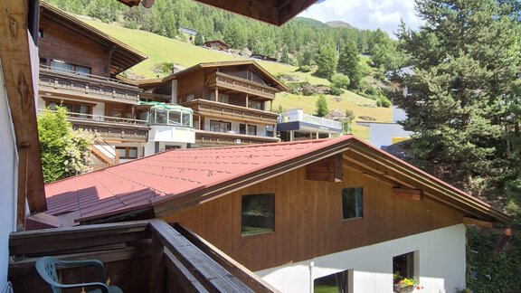 A cozy balcony view of traditional wooden houses and green hills. The sky is blue and the surroundings are sunny. - Appt. Wildschütz - Sölden