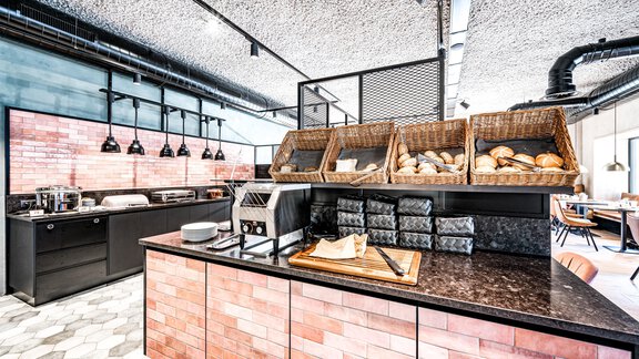 Ein modernes Frühstücksbuffet mit verschiedenen Brotsorten in Körben. Die Einrichtung ist hell und einladend, mit einem klaren, stilvollen Design. - Bäckelar Wirt - Sölden
