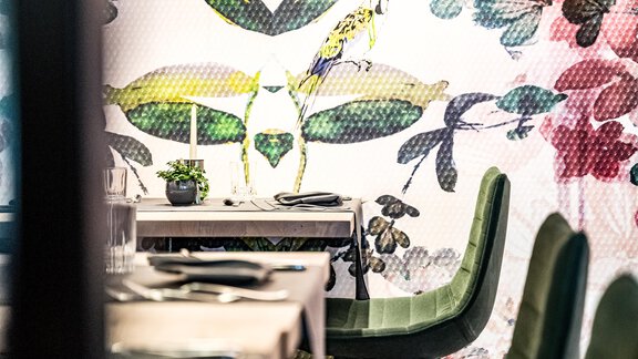 Ein stilvolles Restaurant mit einem floralen Wandmuster und eleganten Stühlen. Der Tisch ist gedeckt und bietet eine gemütliche Atmosphäre. - Bäckelar Wirt - Sölden