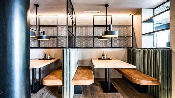 Ein modernes Restaurant mit stilvollen Sitzbänken und Holzstühlen. Die Innenausstattung ist minimalistisch mit gutem Licht und klaren Linien. - Bäckelar Wirt - Sölden