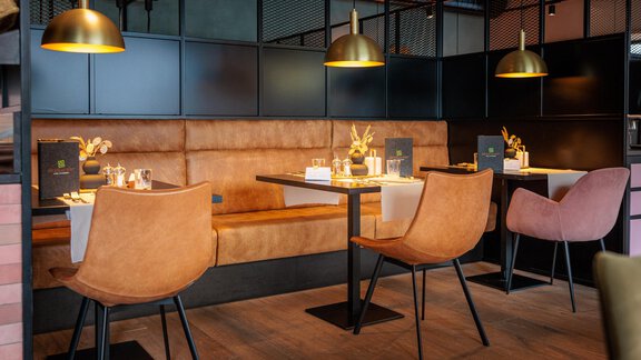 Ein stilvolles Restaurantinterieur mit gemütlichen Sitzbänken und modernen Tischen. Die warmen Farben und die eleganten Leuchten schaffen eine einladende Atmosphäre. - Bäckelar Wirt - Sölden