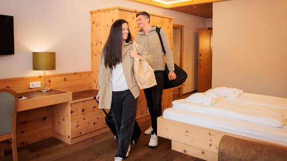 Ein modernes Hotelzimmer mit Holzdekor. Ein Paar betritt den Raum mit Gepäck. - Bäckelar Wirt - Sölden