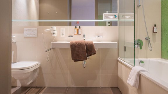 Ein modernes Badezimmer mit Dusche und Badewanne. Handtücher liegen auf dem Waschbecken und es gibt Pflegeprodukte an der Wand. - Bäckelar Wirt - Sölden