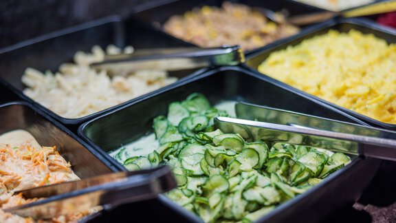 Eine Auswahl an frischem Salat und Beilagen in Schalen. Zu sehen sind Gurkenscheiben, Nudelsalat und Kartoffelsalat. - Bäckelar Wirt - Sölden