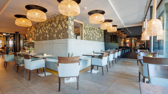 Ein modernes Restaurant mit gemütlichen Tischen und Stühlen. Die warmen Lichter schaffen eine einladende Atmosphäre. - Bäckelar Wirt - Sölden