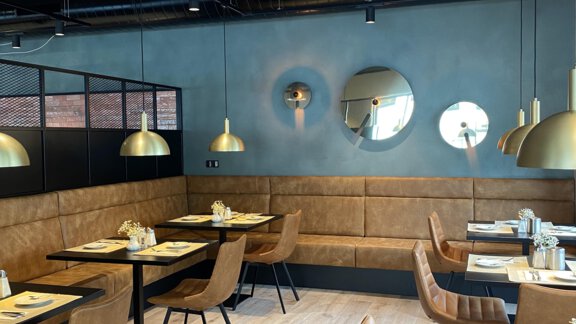Ein modernes Restaurant mit stilvollen Möbeln und einer warmen Farbgestaltung. Es sind runde Spiegel und dekorative Lampen an der Decke sichtbar. - Bäckelar Wirt - Sölden