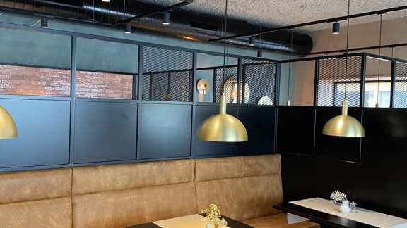 Ein modernes Restaurant mit gemütlichen Sitzgelegenheiten und stilvollen, goldenen Lampen. Die Wände sind in dunklen Tönen gehalten, was eine elegante Atmosphäre schafft. - Bäckelar Wirt - Sölden