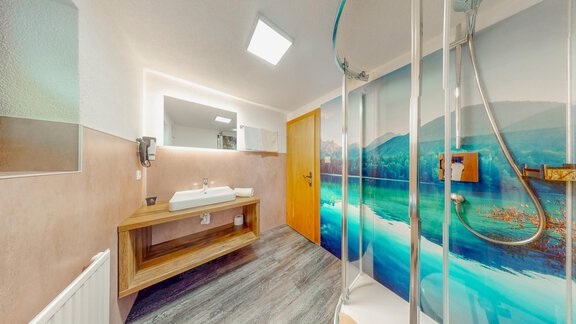 A modern bathroom with a large shower and a wooden washbasin. A wall with a calming landscape motif gives the room a pleasant atmosphere. - Belmonte Sölden - Sölden