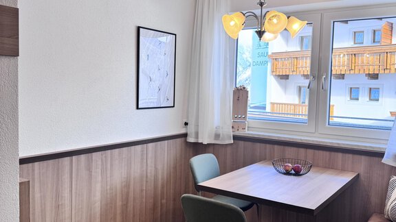 A cozy dining area with a table and two chairs. Large windows let in plenty of daylight. - CASA bianco DUE - Sölden