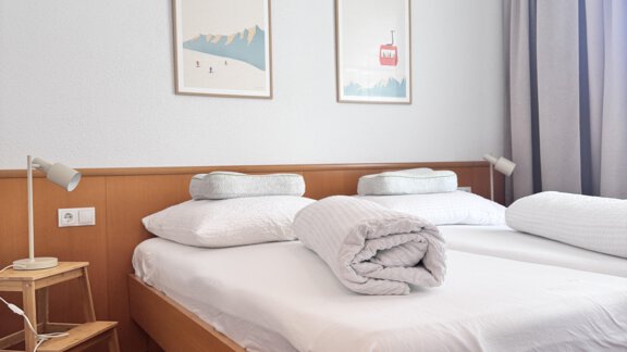 A bright bedroom with a double bed and fresh bedding. Two pictures hang on the wall, while a curtain adorns the window. - CASA bianco DUE - Sölden