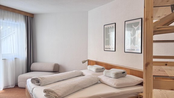 A cozy bedroom with a double bed and an armchair. Pictures hang on the walls, and the room has a modern carpet. - CASA bianco DUE - Sölden