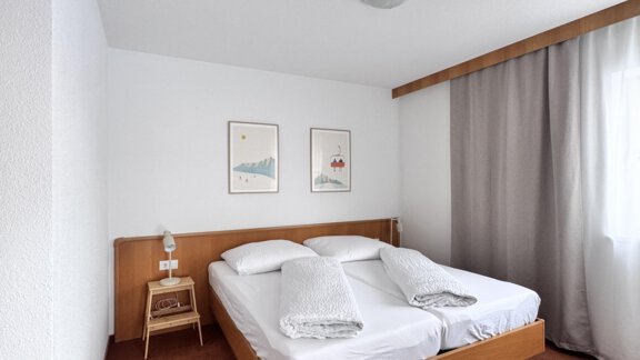 A simple and clean hotel room with two single beds. There is a desk and a large window with curtains. - CASA bianco DUE - Sölden