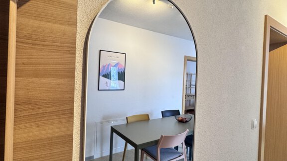 An oval mirror hangs on the wall and reflects an inviting dining area with a table and chairs. The room is bright and cheerfully designed. - CASA bianco DUE - Sölden