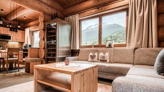 A cozy living room with wooden walls and a view of the mountains. The decor is modern and inviting, with a sofa and a wooden table. - Chalet Resort Sölden - Sölden