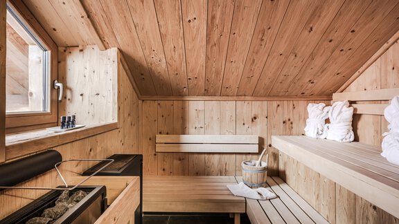 A cozy wooden sauna area with benches and a sauna. Large windows provide plenty of daylight. - Chalet Resort Sölden - Sölden