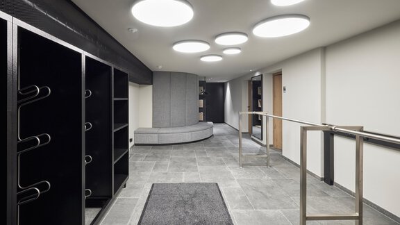 A modern entrance area with bright light and minimalist decor. Gray tiles and simple furniture create an inviting atmosphere. - Chalet White Pearl by MYALPS - Sölden