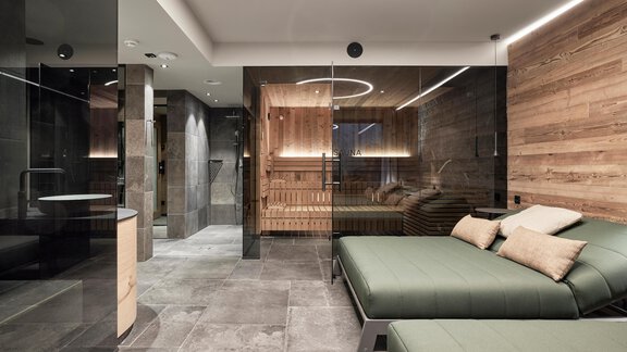 A modern spa with a wood sauna and comfortable loungers. The walls are made of glass and wood, creating a relaxing atmosphere. - Chalet White Pearl by MYALPS - Sölden