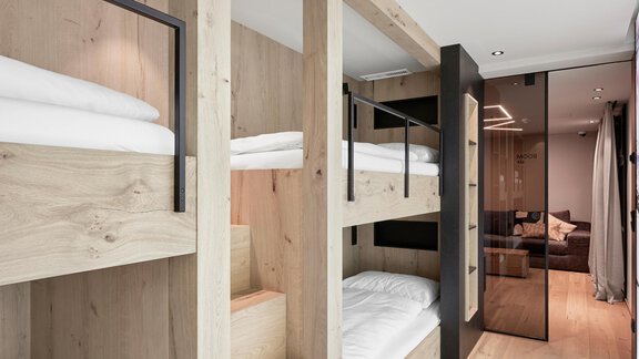 A modern dormitory with wooden bunk beds. The room has a bright and friendly atmosphere. - Chalet White Pearl by MYALPS - Sölden