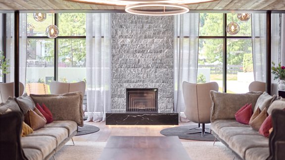 A stylishly decorated room with comfortable sofas and a modern fireplace. Large windows let in plenty of light and create an inviting atmosphere. - Chalet White Pearl by MYALPS - Sölden