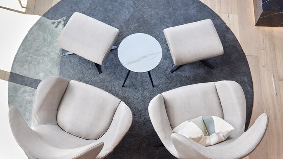 An elegant seating area with two comfortable armchairs and a small table in the middle. The floor is brightly and modernly designed. - Chalet White Pearl by MYALPS - Sölden