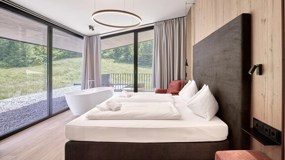 A modern bedroom with a large window and a view of nature. The room is stylishly furnished with a double bed and cozy furniture. - Chalet White Pearl by MYALPS - Sölden
