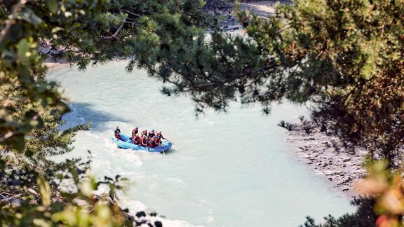 A group of people is rafting on a clear river. Surrounded by trees and natural landscape, the scene offers a sense of adventure. - Chalet White Pearl by MYALPS - Sölden