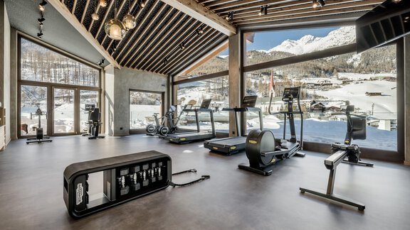 Ein modernes Fitnessstudio mit Blick auf die Berge. Die großen Fenster lassen viel Licht herein und zeigen eine beeindruckende Aussicht. - Das Central - Alpine . Luxury . Life - Sölden