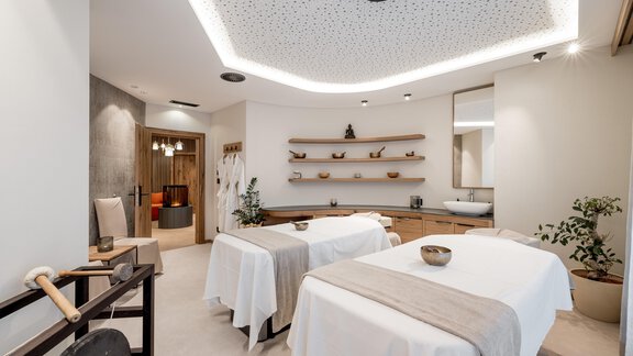 Ein eleganter Wellnessbereich mit zwei Massagebetten. Die Umgebung ist hell und modern gestaltet, mit dekorativen Elementen und Pflanzen. - Das Central - Alpine . Luxury . Life - Sölden
