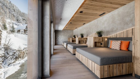 Ein modernes Zimmer mit Holz- und Betonelementen. Große Fenster bieten einen Blick auf die verschneite Landschaft. - Das Central - Alpine . Luxury . Life - Sölden