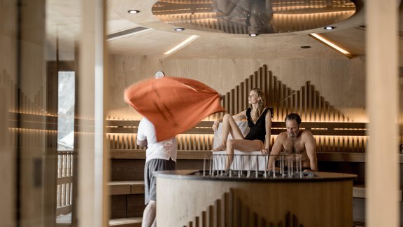 Ein modernes Spa mit Holzdekor und einer runden Sitzfläche. Drei Personen entspannen sich und genießen die Atmosphäre. - Das Central - Alpine . Luxury . Life - Sölden