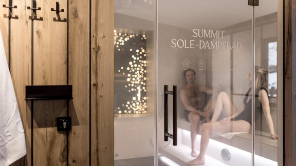 Ein moderner Wellnessbereich mit einer Dampfkabine aus Glas. Im Inneren entspannen zwei Personen in einer ruhigen Atmosphäre. - Das Central - Alpine . Luxury . Life - Sölden