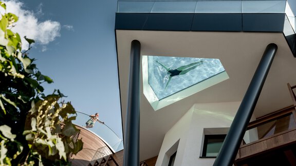 Ein modernes Gebäude mit einem gläsernen Dachfenster. Darunter ist eine Person im Wasser zu sehen. - Das Central - Alpine . Luxury . Life - Sölden