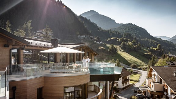 Ein modernes Gebäude mit einem Pool auf der Terrasse und Blick auf die Berge. Die Umgebung ist grün und sonnig, ideal für einen entspannten Aufenthalt. - Das Central - Alpine . Luxury . Life - Sölden