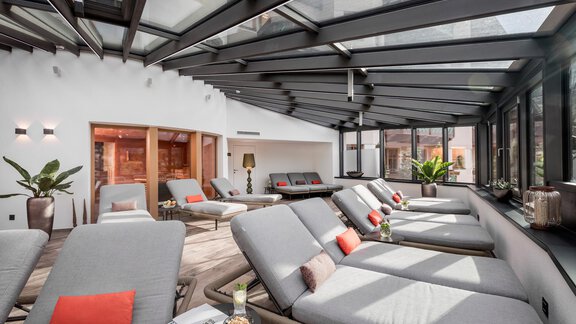 Ein heller Ruheraum mit Liegen und großen Fenstern. Die entspannende Atmosphäre wird durch Pflanzen und dekorative Kissen ergänzt. - Das Central - Alpine . Luxury . Life - Sölden