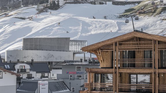 A winter mountain panorama with snow-covered slopes and a modern building view in the foreground. The landscape is calm and inviting for winter sports activities. - Edelweiss echt.charmant. - Sölden