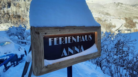 A sign that reads "Vacation Home Anna," covered in snow. In the background, there are snow-covered mountains and a blue sky. - Ferienhaus Anna - Sölden